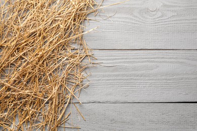 Pile of dried straw on grey wooden table, top view. Space for text