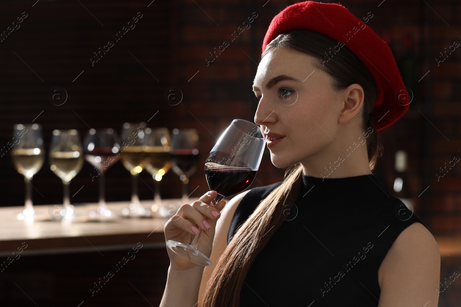 Photo of Beautiful woman with glass of red wine against blurred background