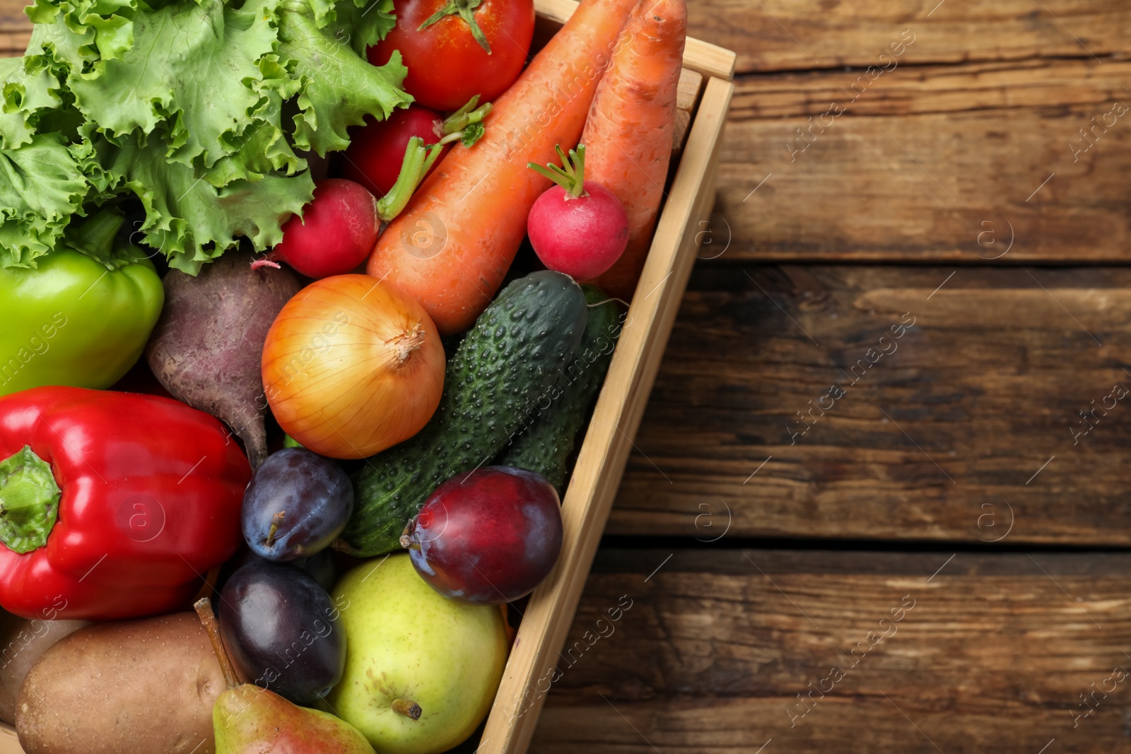 Photo of Crate full of different vegetables and fruits on wooden table, top view. Harvesting time