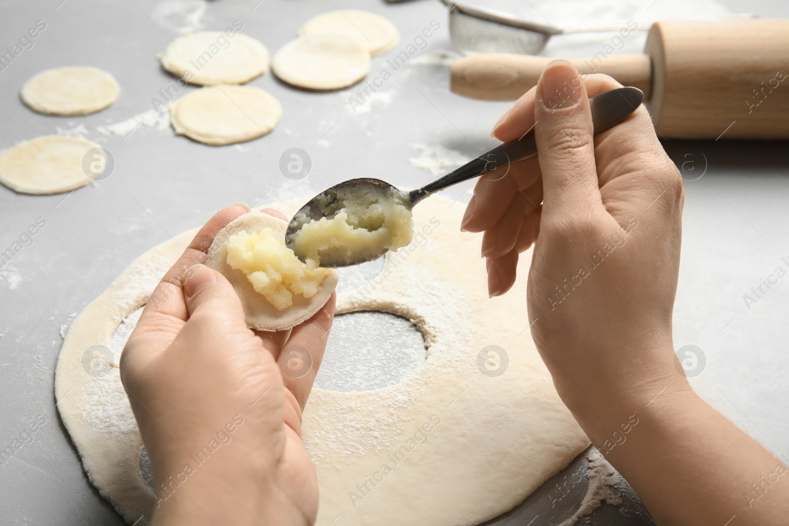 Photo of Woman cooking delicious dumplings over table, closeup