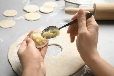 Photo of Woman cooking delicious dumplings over table, closeup