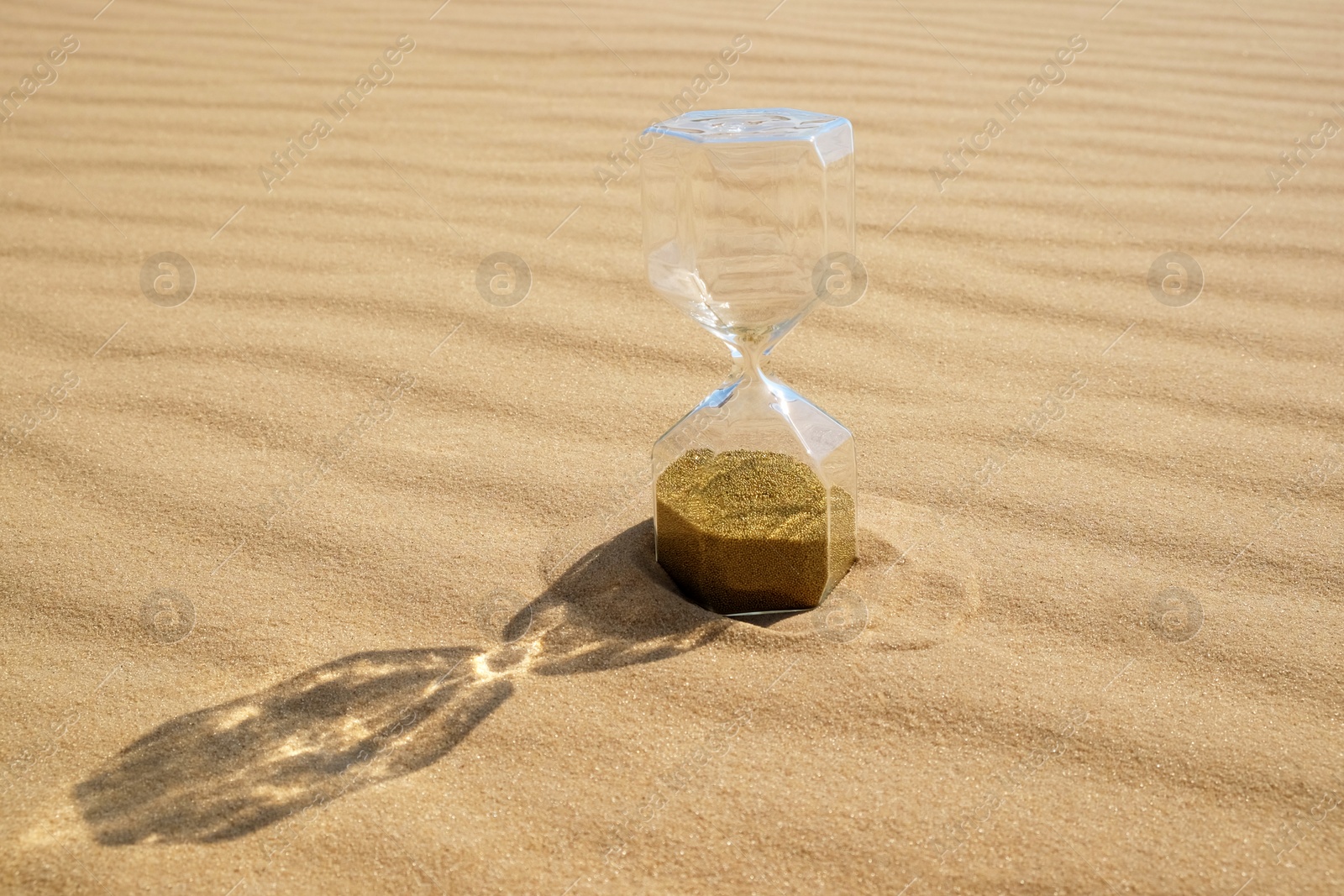 Photo of Hourglass with flowing sand in desert on sunny day. Space for text