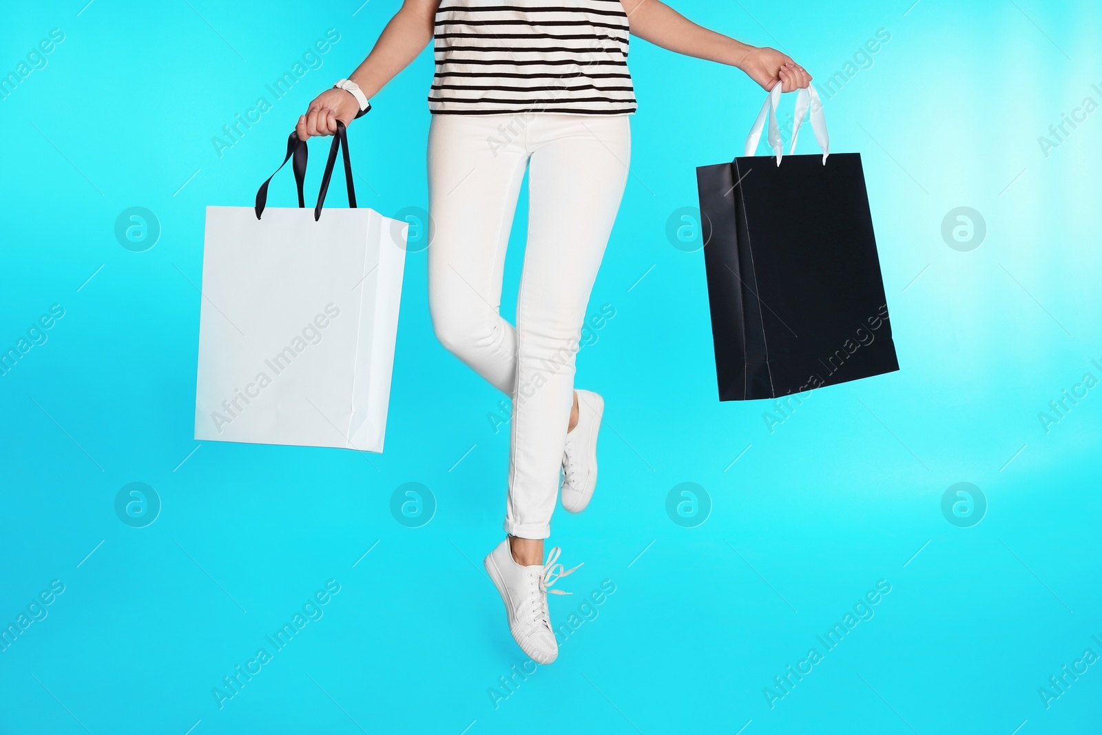 Photo of Woman jumping with paper shopping bags on color background. Mock up for design