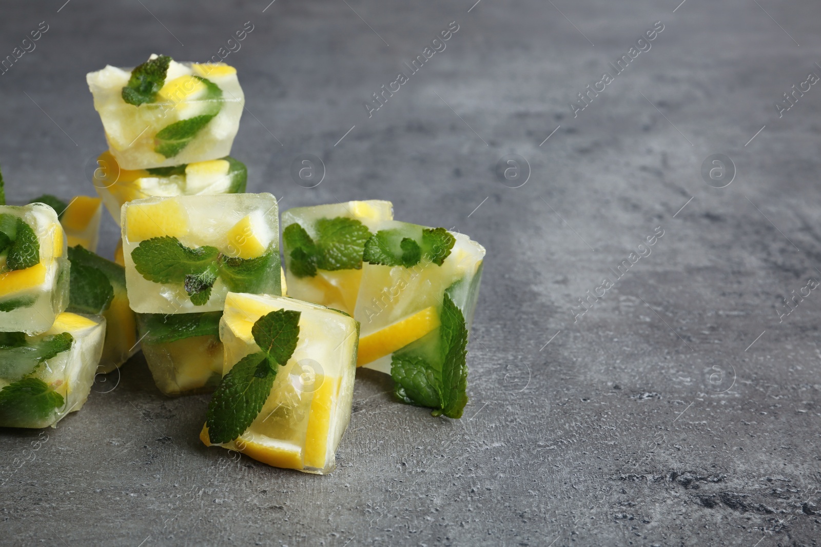 Photo of Ice cubes with mint and lemon on grey background. Space for text