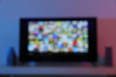 Photo of Blurred view of modern TV set on table indoors