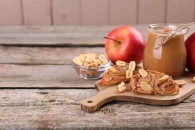 Photo of Fresh apples with peanut butter on wooden table, space for text