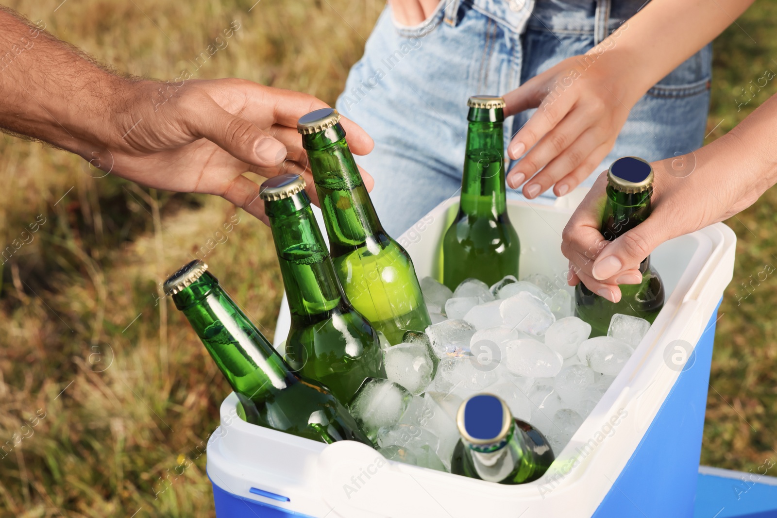 Photo of Friends taking bottles of beer from cool box outdoors, closeup