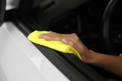 Photo of Woman cleaning car door with rag, closeup