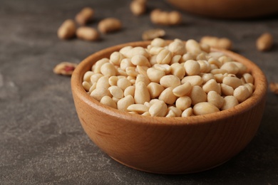 Photo of Shelled peanuts in wooden bowl on table