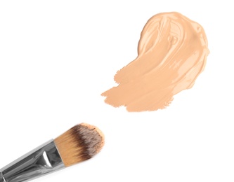 Sample of liquid foundation and makeup brush on white background, top view