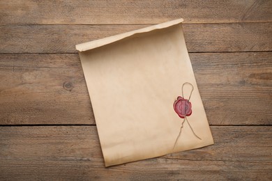 Photo of Sheet of old parchment paper with wax stamp on wooden table, top view. Space for design