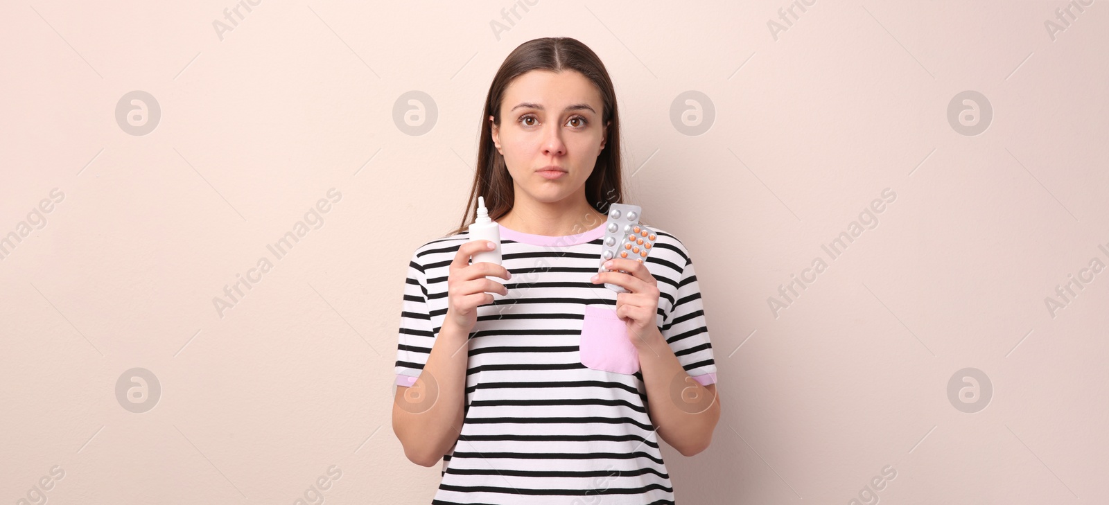 Photo of Woman with nasal spray and pills on beige background