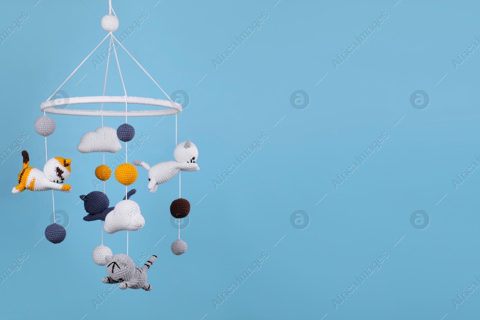 Photo of Cute baby crib mobile on light blue background, space for text