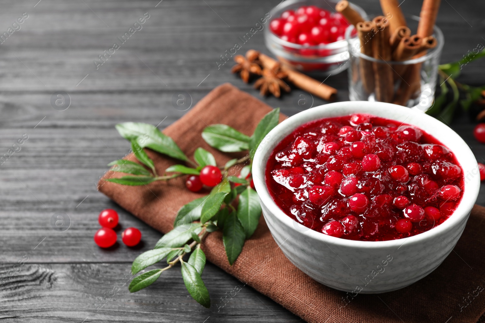 Photo of Fresh cranberry sauce served in bowl on grey wooden table, space for text