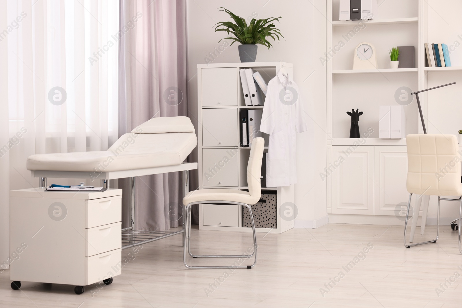 Photo of Modern medical office interior with doctor's workplace and examination table