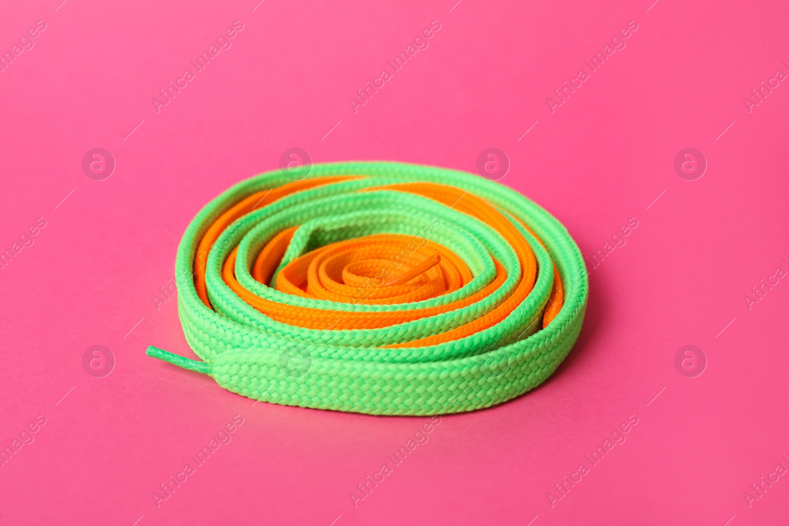 Photo of Mint and orange shoe laces on pink background