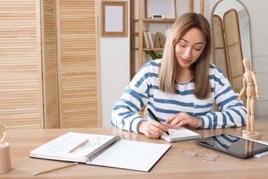 Photo of Woman drawing in sketchbook with pen at wooden table indoors