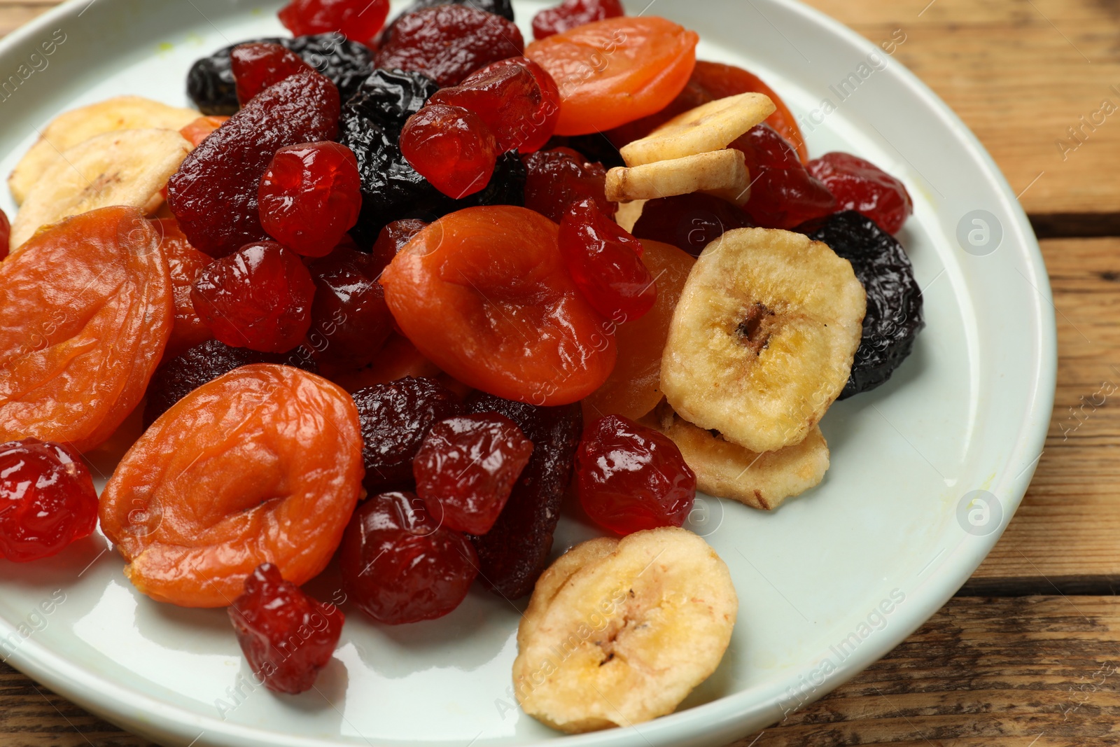 Photo of Mix of delicious dried fruits on wooden table, closeup