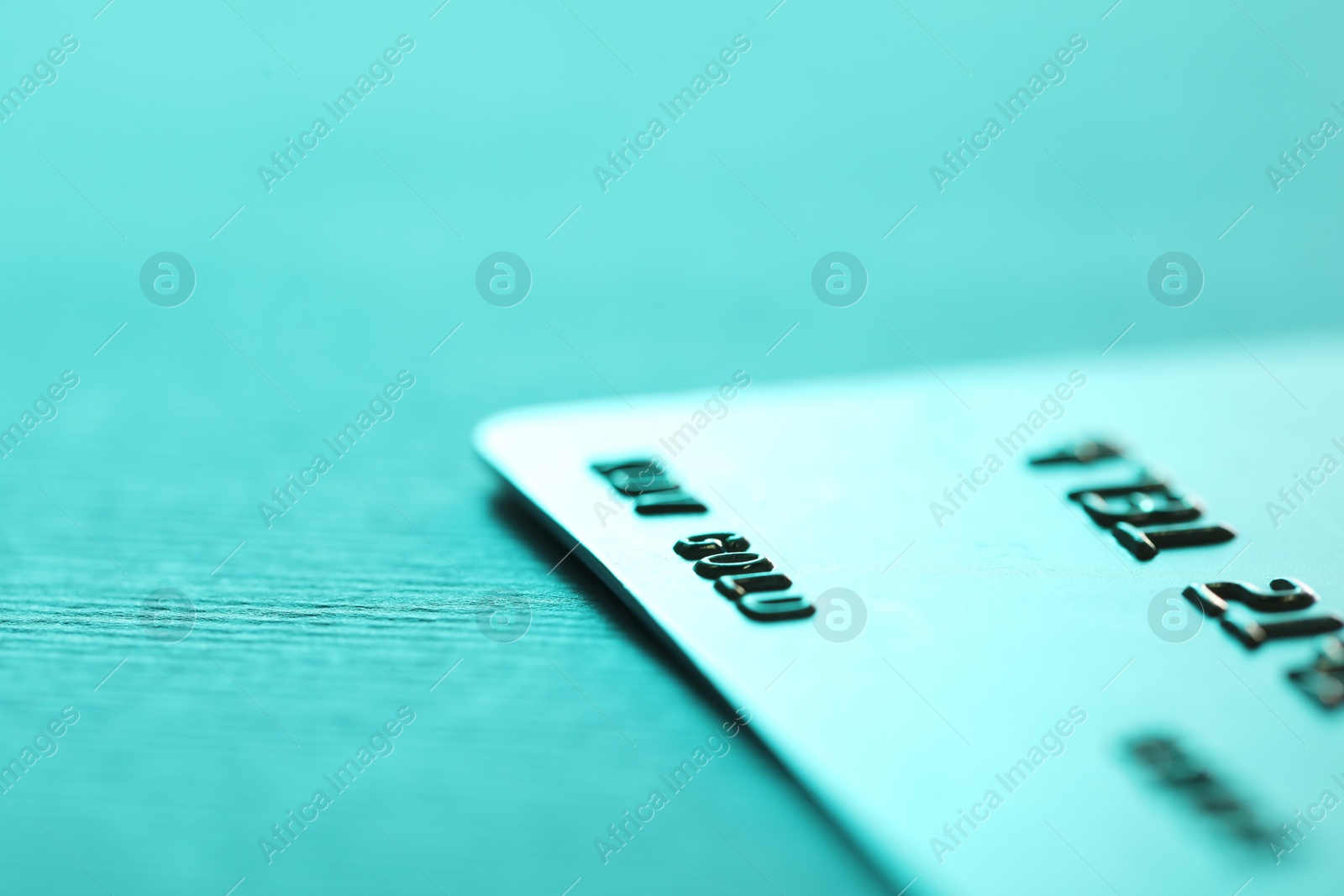 Photo of One credit card on turquoise background, closeup. Space for text