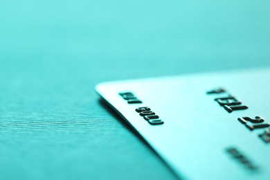 Photo of One credit card on turquoise background, closeup. Space for text