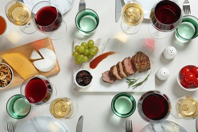 Photo of Wine and snacks served for dinner on light table, flat lay