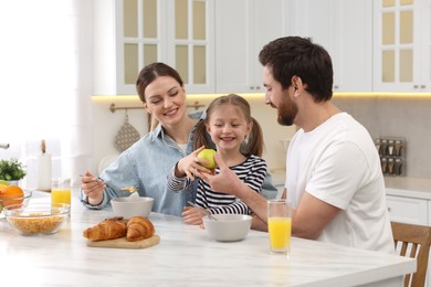 Photo of Happy family having breakfast at table in kitchen