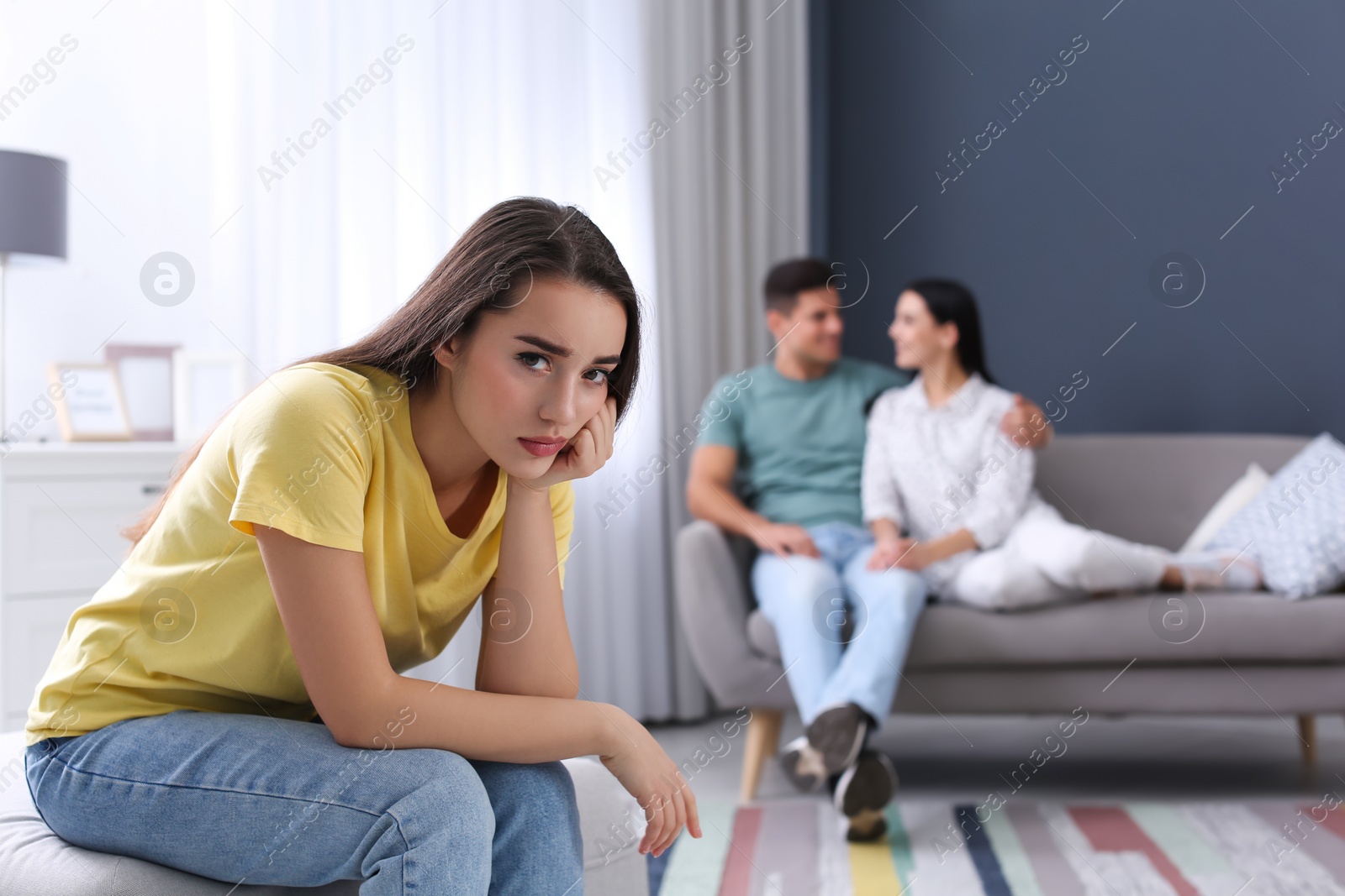 Photo of Unhappy woman feeling jealous while couple spending time together at home