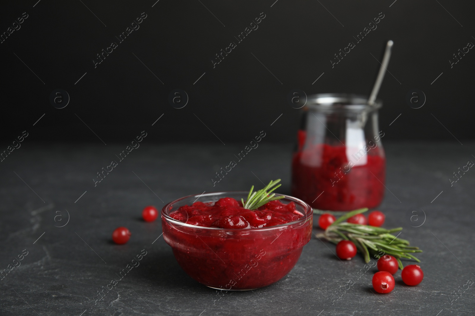 Photo of Bowl of cranberry sauce with rosemary on grey table