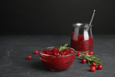 Photo of Bowl of cranberry sauce with rosemary on grey table