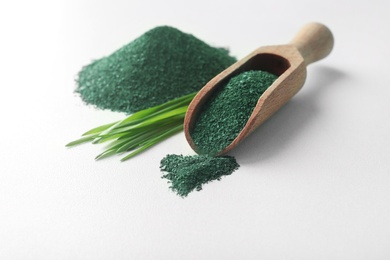 Photo of Composition with spirulina algae powder and grass isolated on white