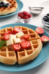 Photo of Tasty Belgian waffles with fresh berries served on white table, closeup