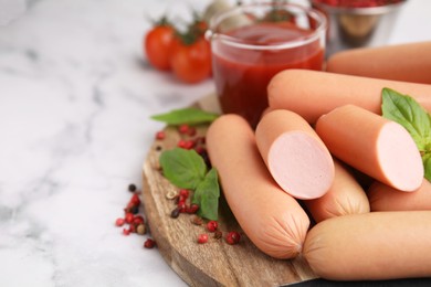 Photo of Delicious boiled sausages, basil and peppercorns on white marble table, closeup. Space for text