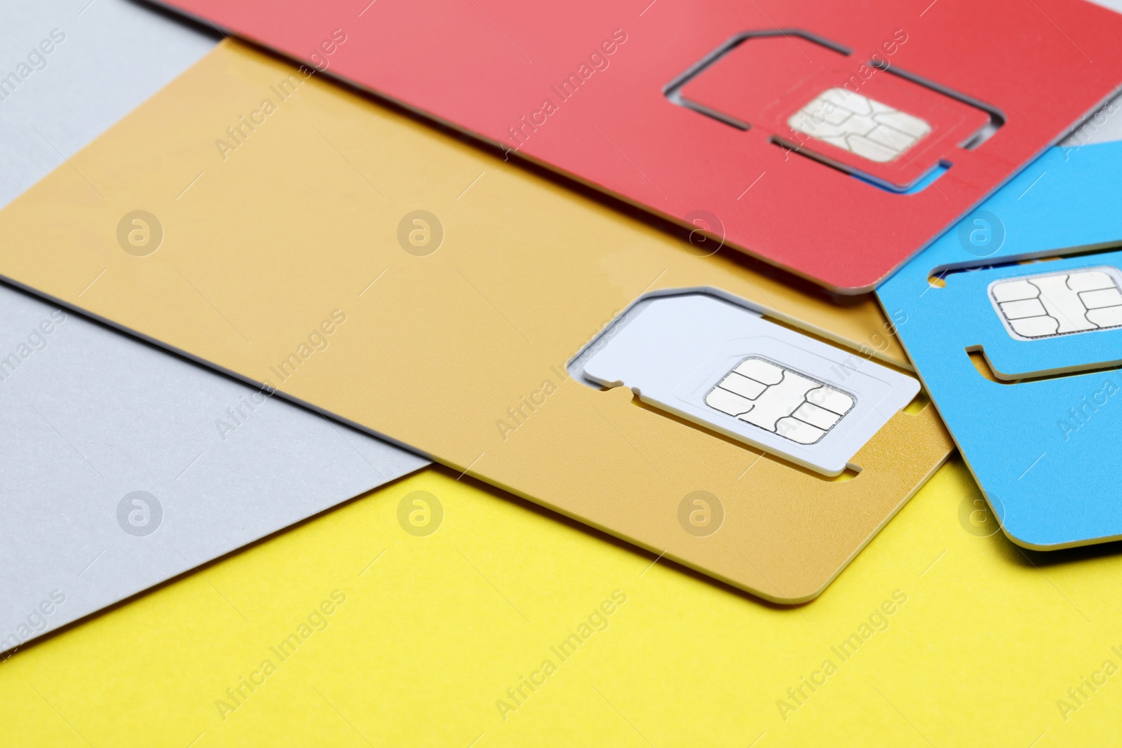Photo of Different SIM cards on yellow background, closeup
