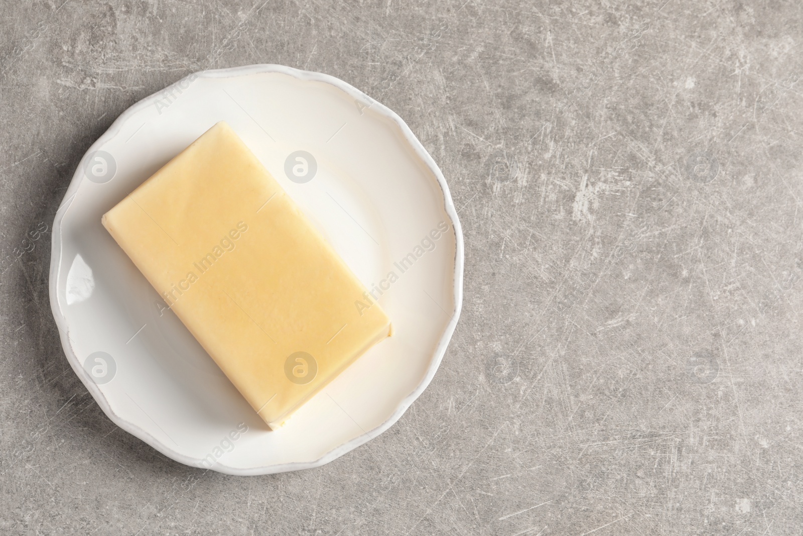 Photo of Plate with fresh butter and space for text on grey background, top view