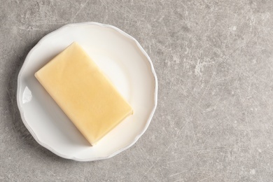 Plate with fresh butter and space for text on grey background, top view