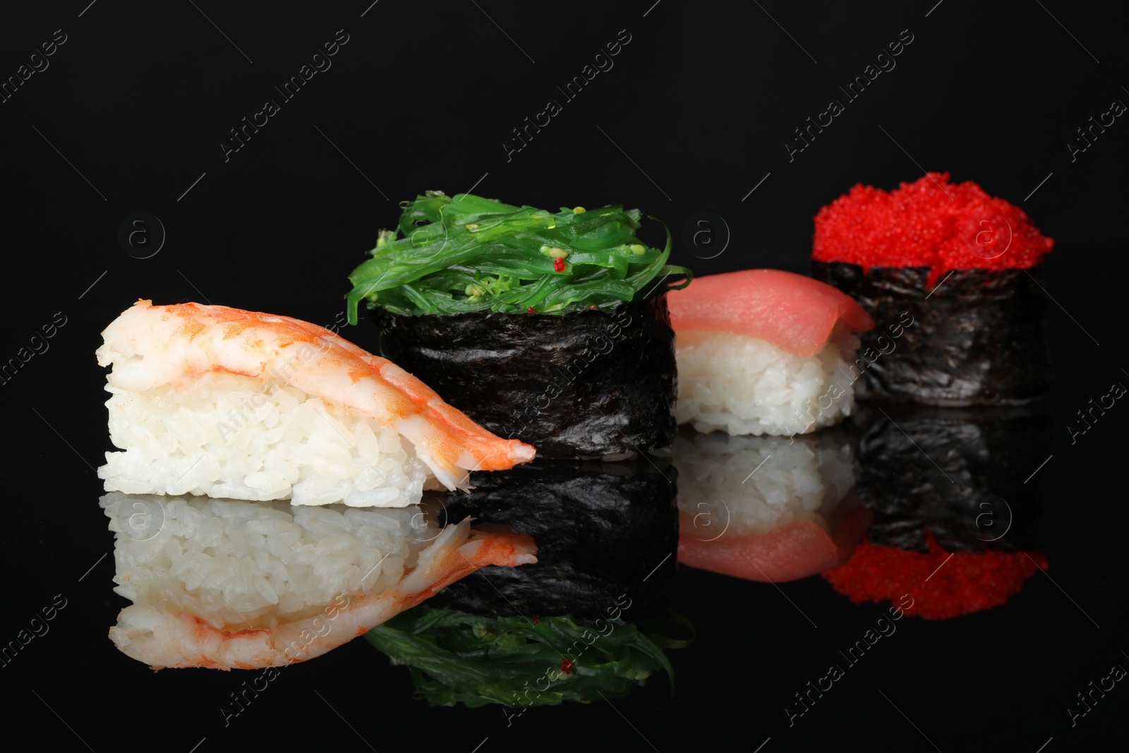 Photo of Set of delicious sushi on black mirror surface