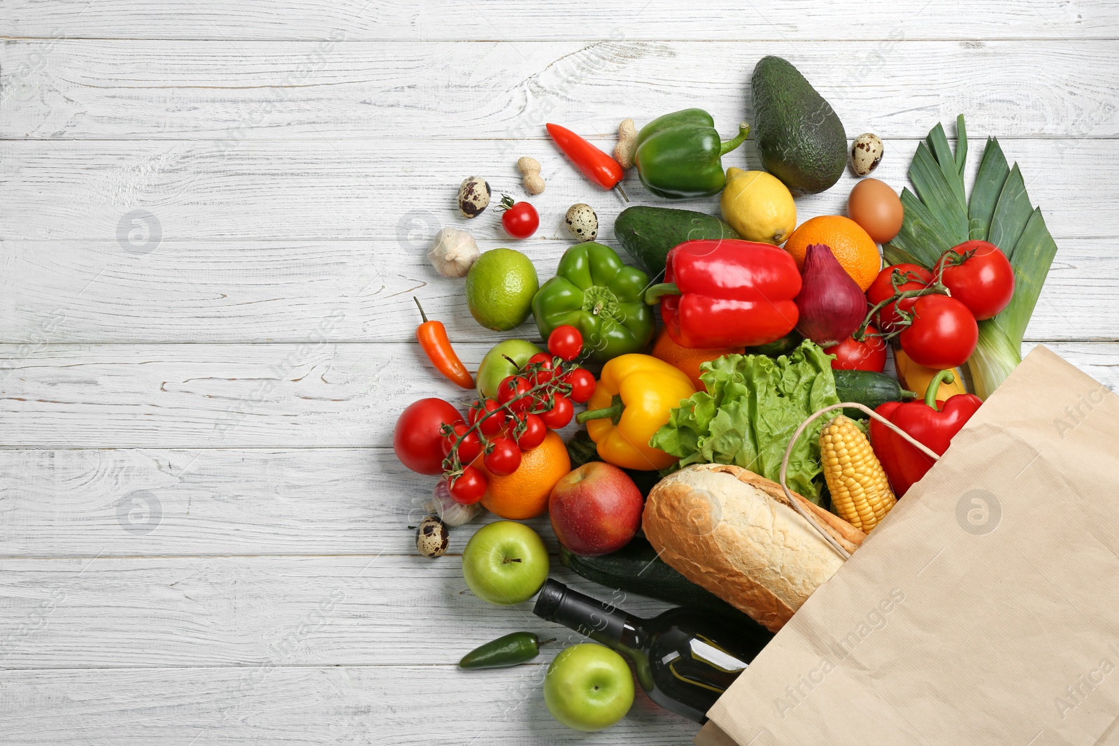 Photo of Paper bag with different groceries on white wooden table, flat lay. Space for text