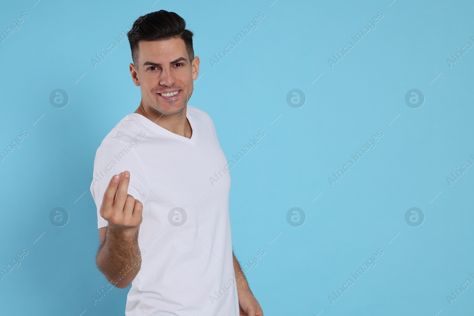 Photo of Handsome man snapping fingers on light blue background. Space for text