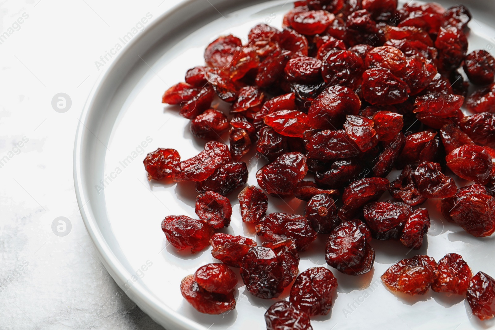 Photo of Plate with cranberries on table, closeup. Dried fruit as healthy snack