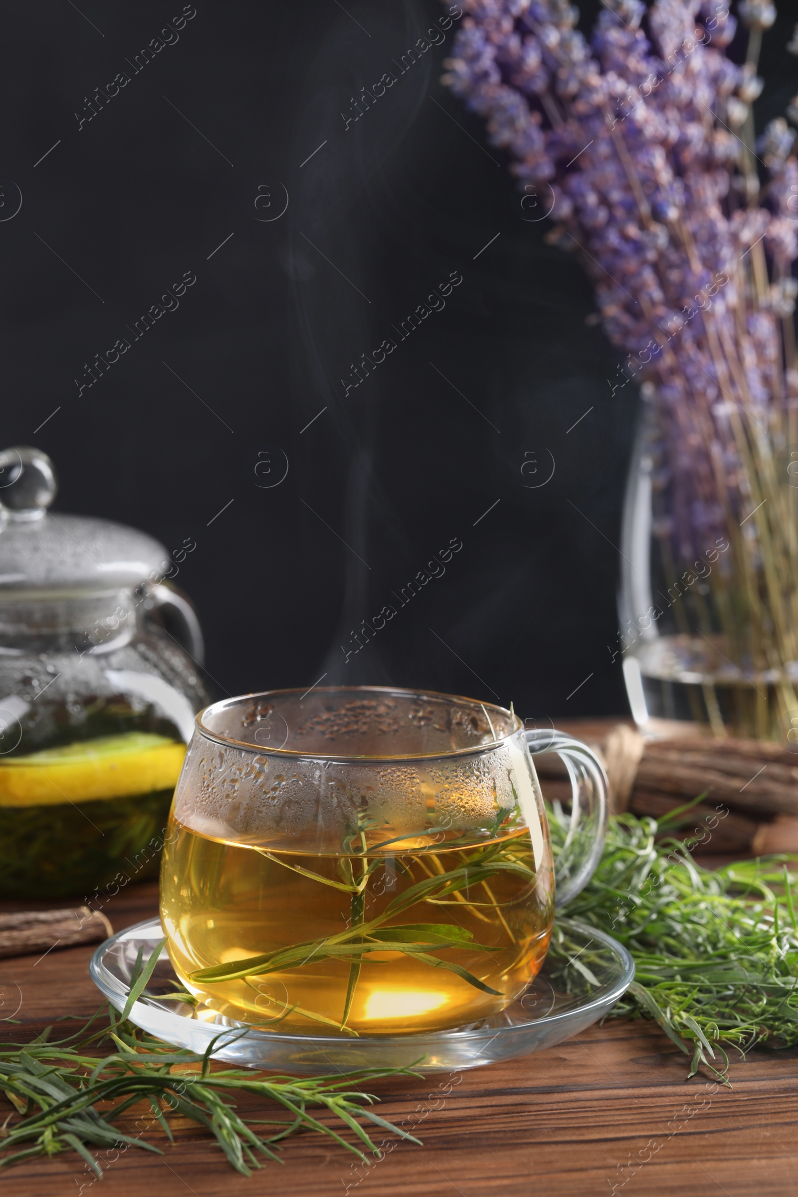 Photo of Homemade herbal tea and fresh tarragon leaves on wooden table