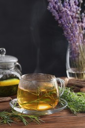 Photo of Homemade herbal tea and fresh tarragon leaves on wooden table