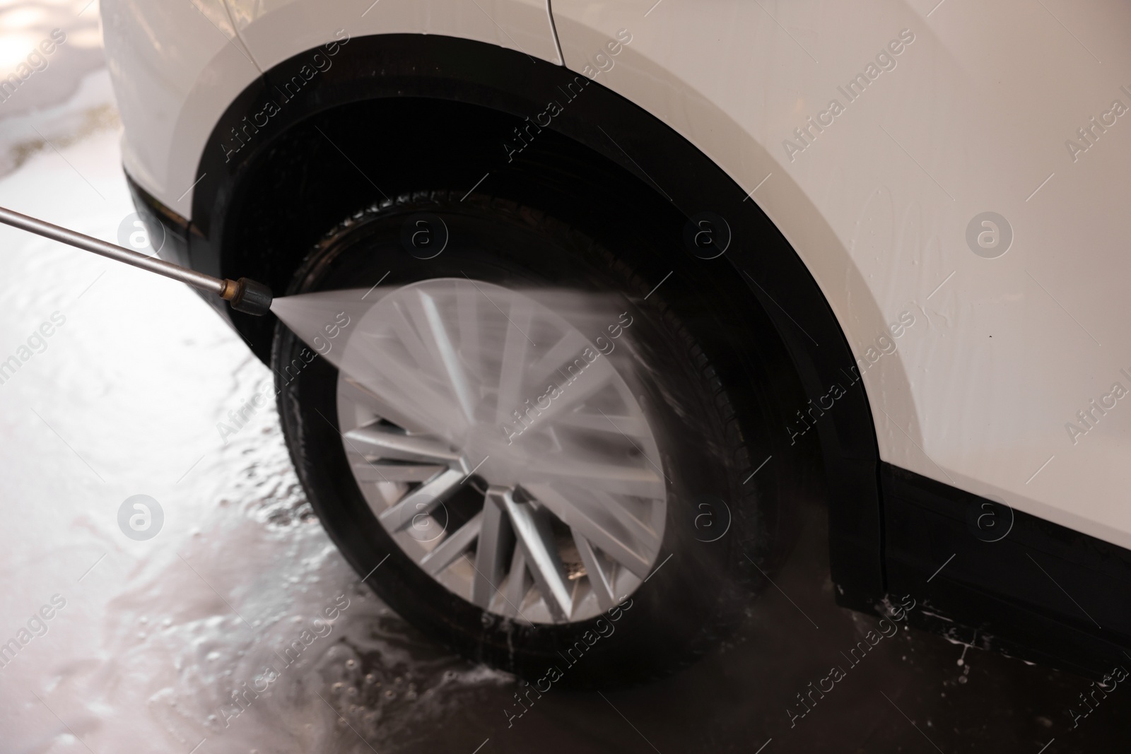 Photo of Washing auto with high pressure water jet at outdoor car wash, closeup