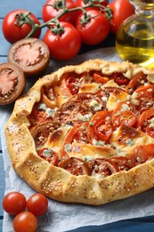 Tasty galette with tomato and cheese (Caprese galette) on blue wooden table, closeup