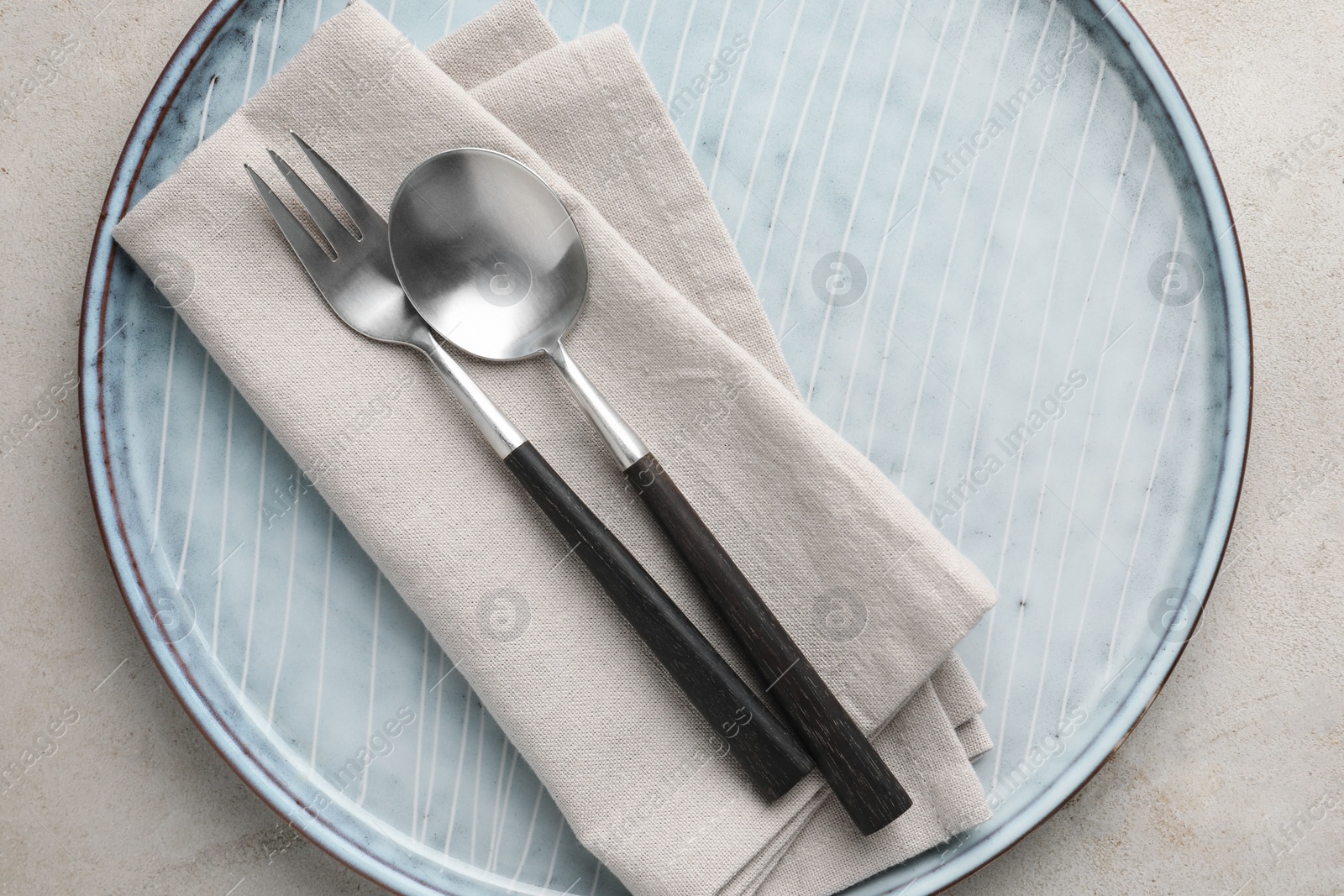 Photo of Stylish setting with cutlery, napkin and plate on light grey table, top view