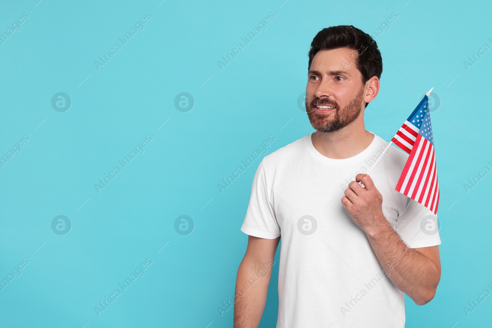 Photo of 4th of July - Independence Day of USA. Happy man with American flag on light blue background, space for text