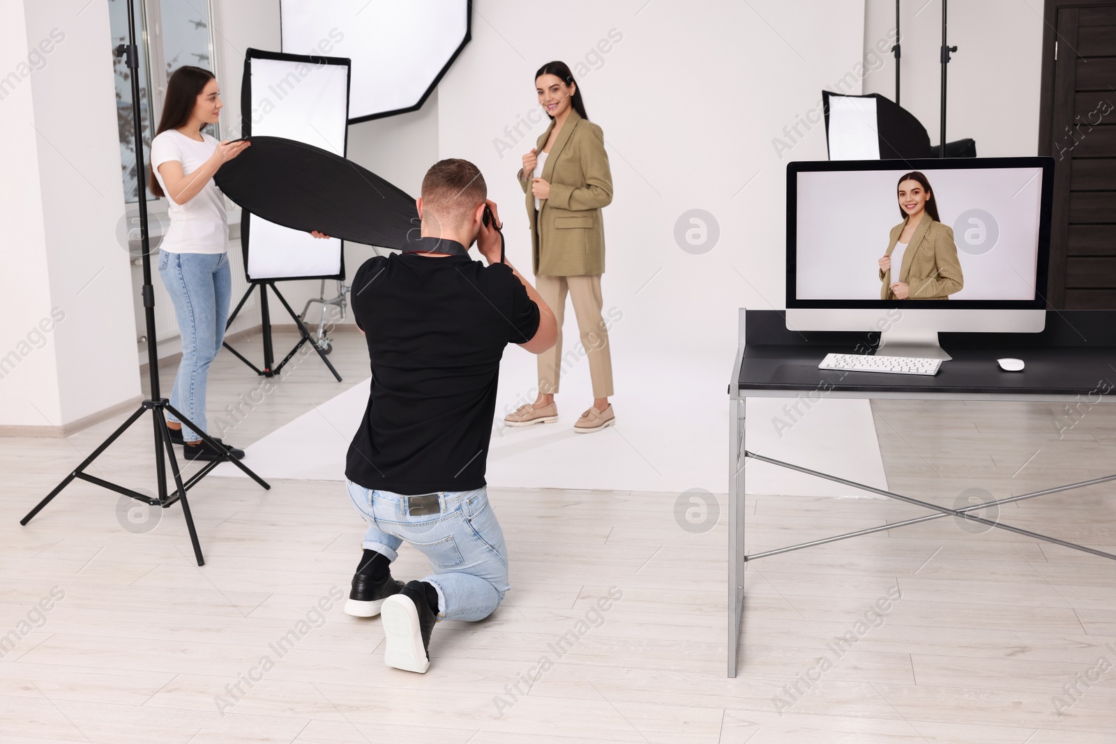 Photo of Professional photographer and assistant working with beautiful model in modern photo studio