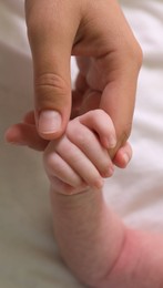 Photo of Mother and her newborn baby on bed, closeup of hands
