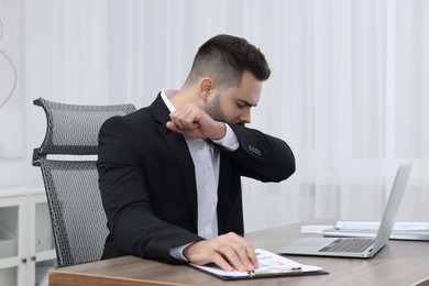 Photo of Sick man coughing at workplace in office