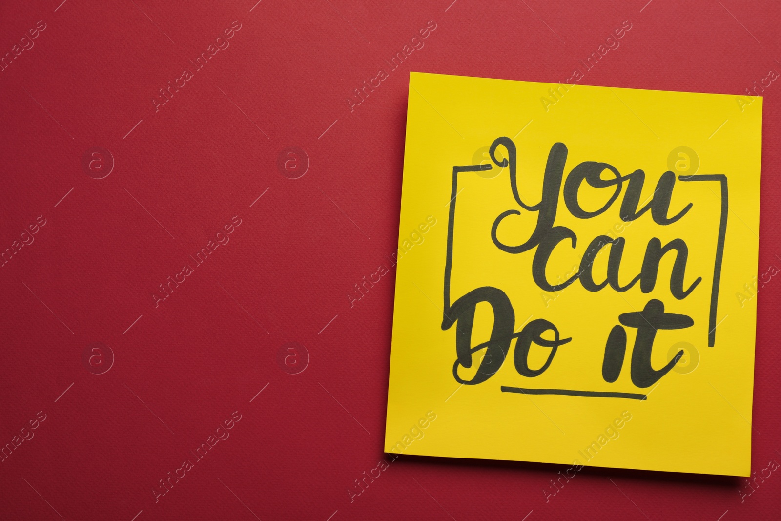 Photo of Yellow card with motivational phrase You Can Do It on burgundy background, top view. Space for text