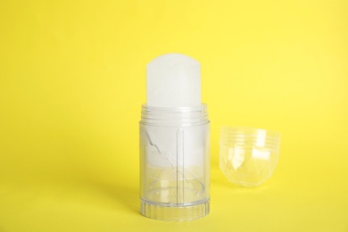 Photo of Natural crystal alum stick deodorant and cap on yellow background